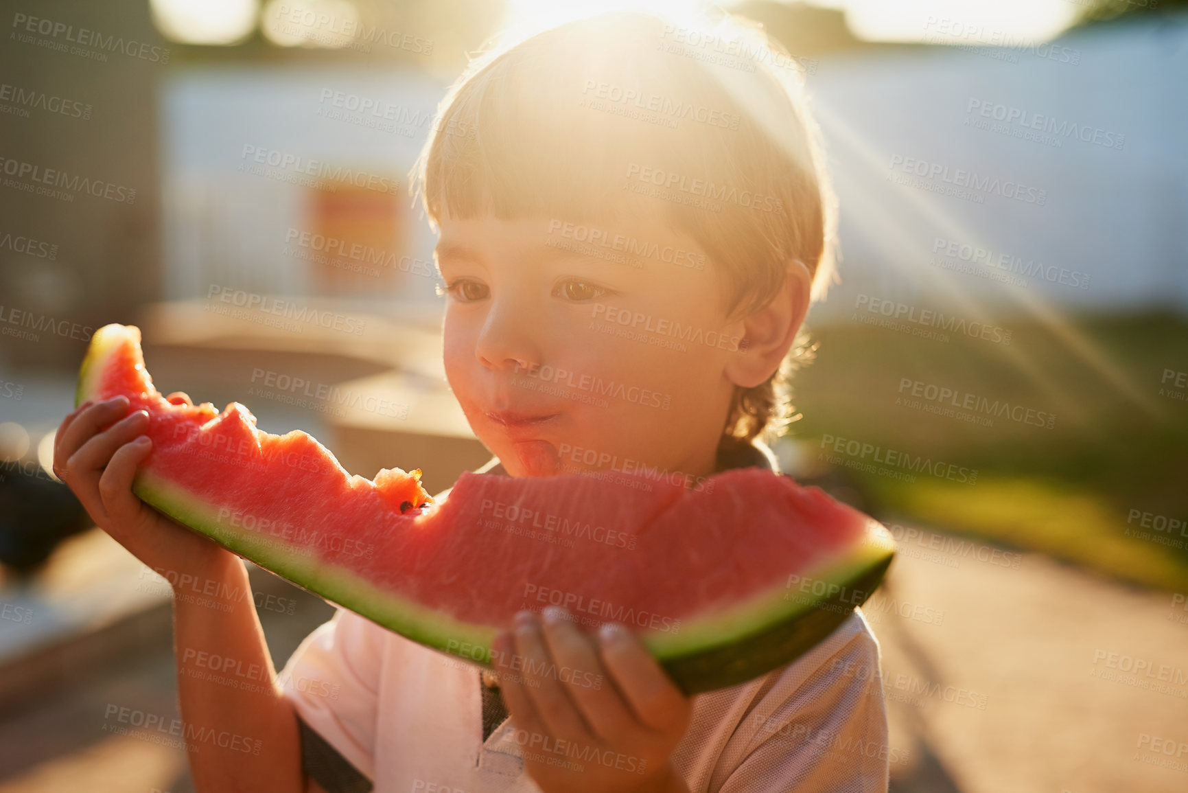 Buy stock photo Boy, child and eating watermelon in backyard, summer or outdoor for wellness, nutrition and holiday. Kid, fruit and hungry with diet, mess and memory for vacation with sunshine on lawn at family home