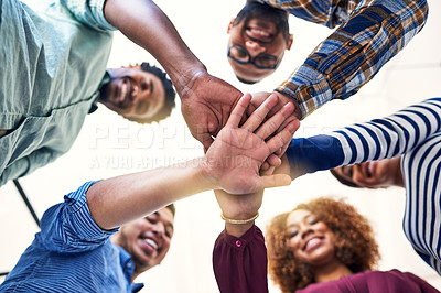 Buy stock photo Low angle shot of a team of designers joining their hands together in unity