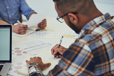 Buy stock photo Cropped shot of a young designer writing notes during a meeting in an office