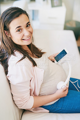 Buy stock photo Shot of a woman wearing headphones over her pregnant belly