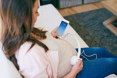 Buy stock photo Relax, phone and pregnant woman on sofa with headphones on stomach for child development in home. Pregnancy, growth and mom on couch with smartphone, sound and music streaming for bonding with baby