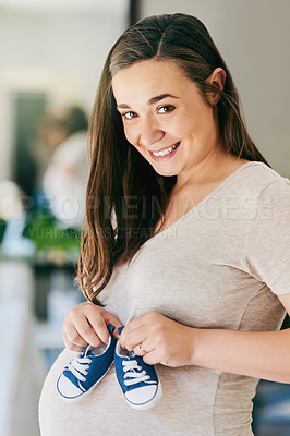 Buy stock photo Cropped shot of a pregnant woman holding baby shoes against her belly