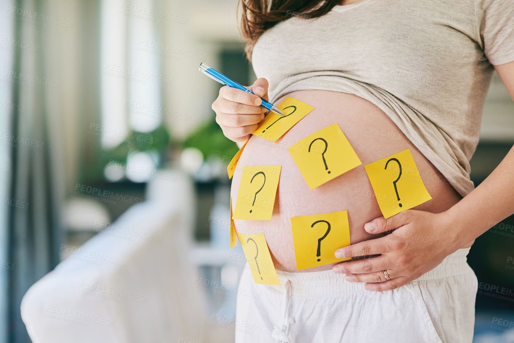 Buy stock photo Shot of a woman with sticky notes with question marks on her pregnant belly
