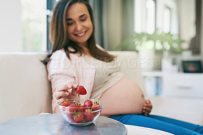 Buy stock photo Shot of a pregnant woman snacking on strawberries