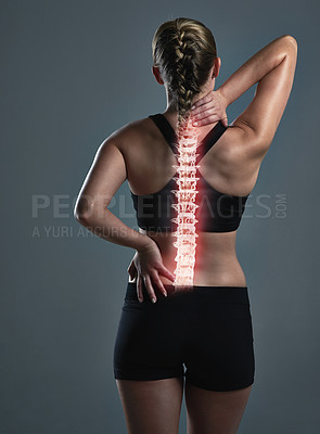 Buy stock photo Rearview shot of a sporty young woman holding her back in pain