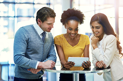 Buy stock photo Cropped shot of a diverse group of businesspeople working together on a digital tablet in an office
