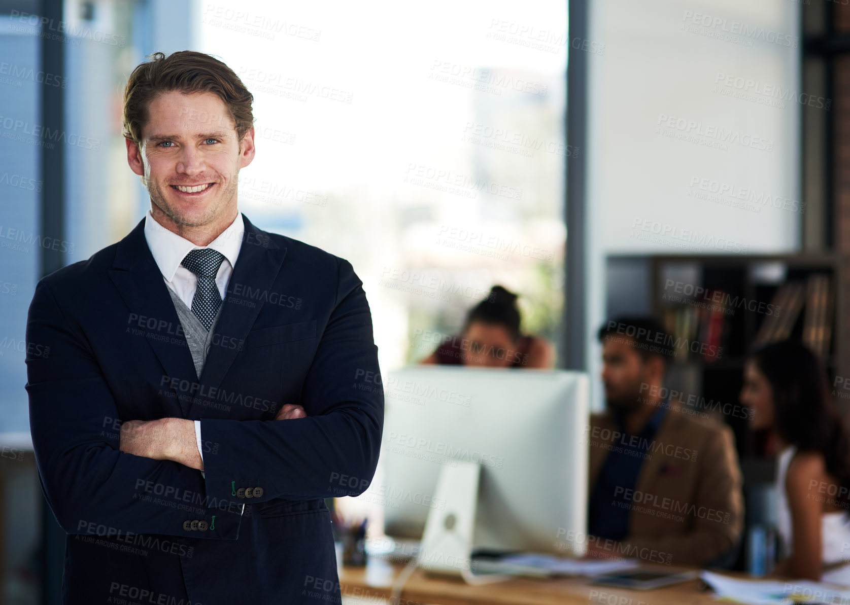 Buy stock photo Portrait of a young businessman standing in an office with his colleagues in the background