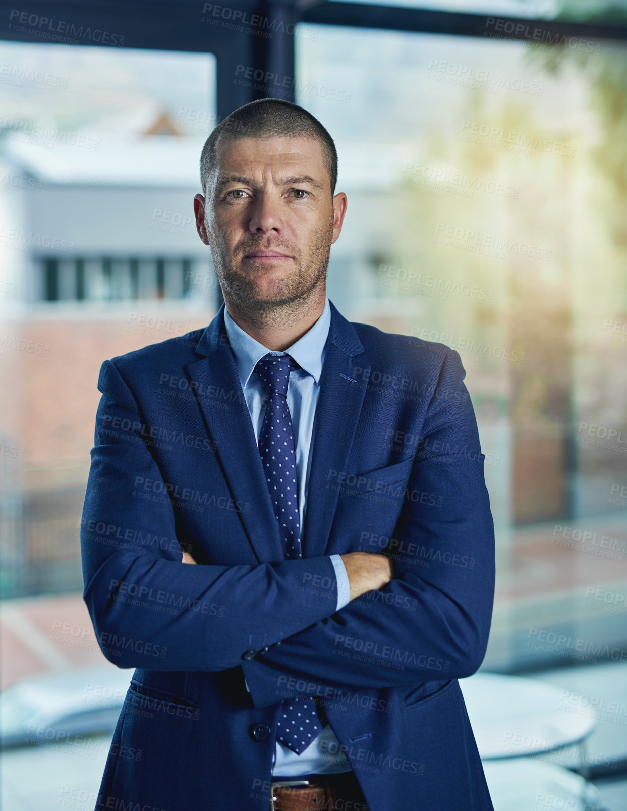 Buy stock photo Cropped portrait of handsome businessman standing with his arms folded in the office