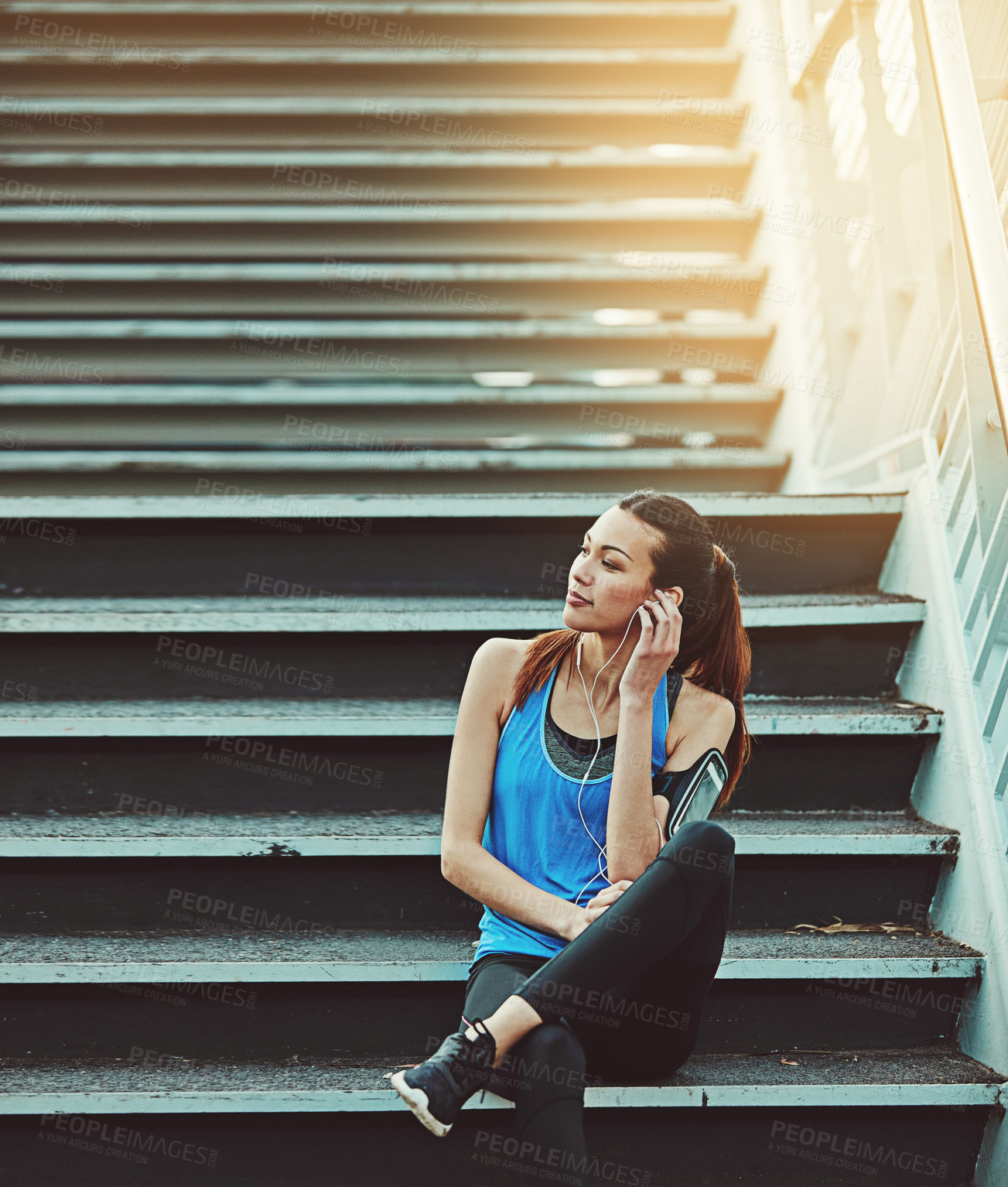 Buy stock photo Girl, runner and earphones on stairs in town, streaming music and smile with training in summer. Woman, rest and exhausted with fitness challenge, audio subscription or exercise with burnout in city