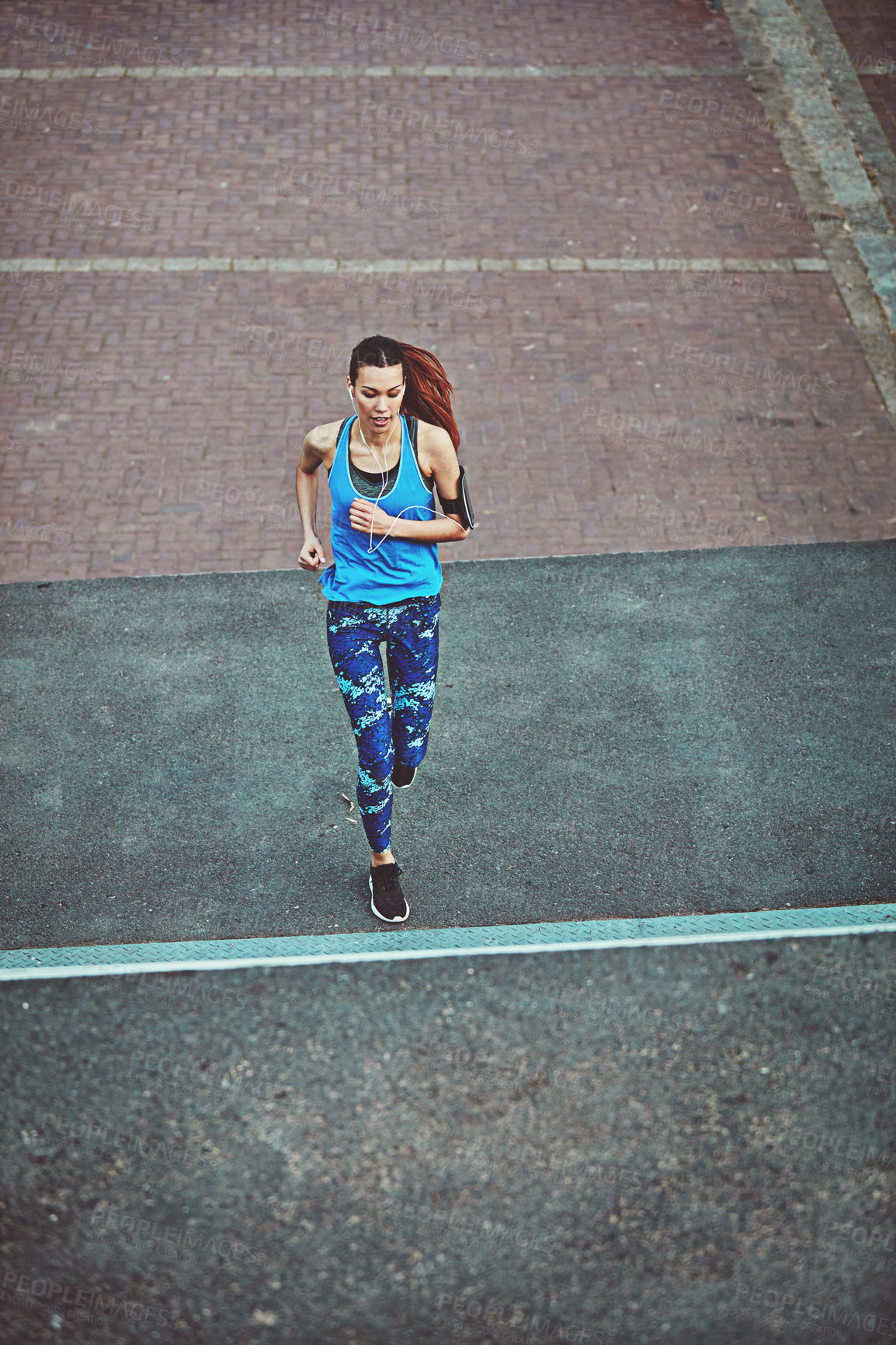 Buy stock photo Woman, exercise and running in street, above and training for fitness, health and speed in city. Girl, person or runner with earphones, phone and audio streaming subscription in road for workout