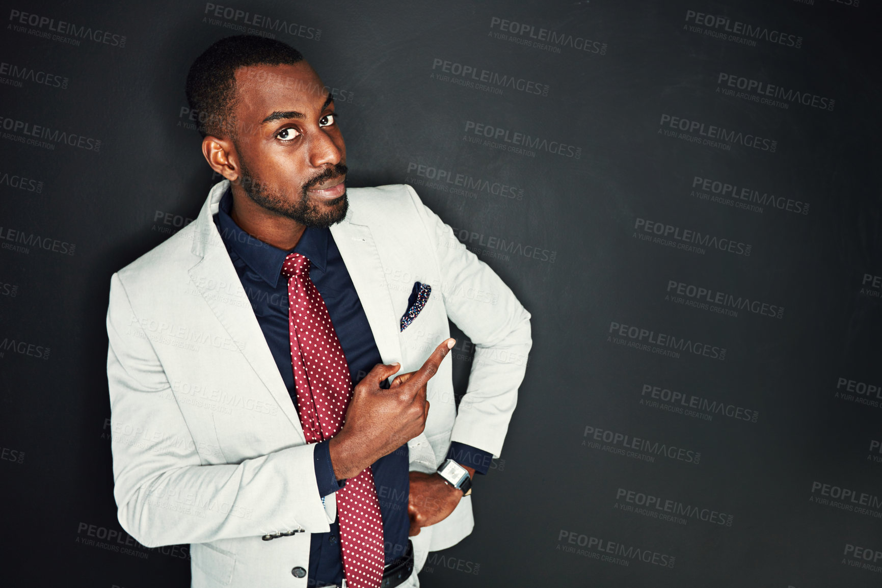 Buy stock photo Portrait of a young businessman pointing against a dark background