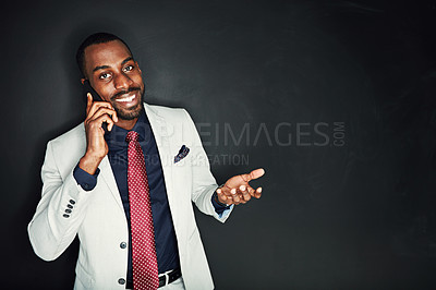 Buy stock photo Portrait of a young businessman talking on a cellphone against a dark background