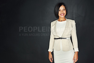 Buy stock photo Portrait of a confident young businesswoman standing against a dark background