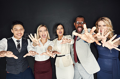 Buy stock photo Portrait of a group of businesspeople with their hands outstretched against a dark background