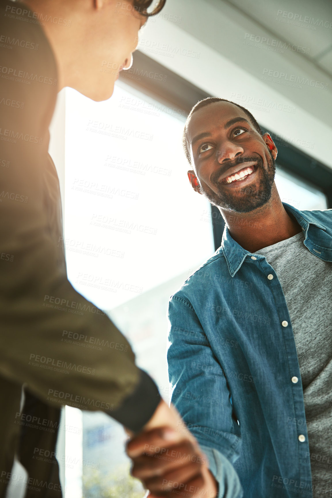 Buy stock photo Low angle shot of two young businessmen shaking hands in the office