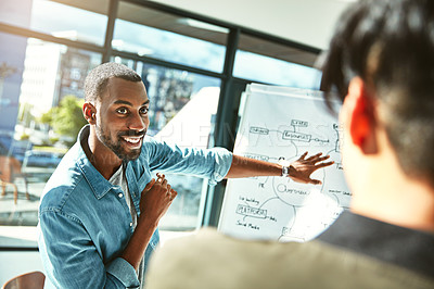 Buy stock photo Shot of two young businessmen brainstorming with a whiteboard in the office