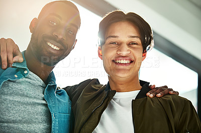 Buy stock photo Portrait of two happy colleagues posing with their arms around each other in the office