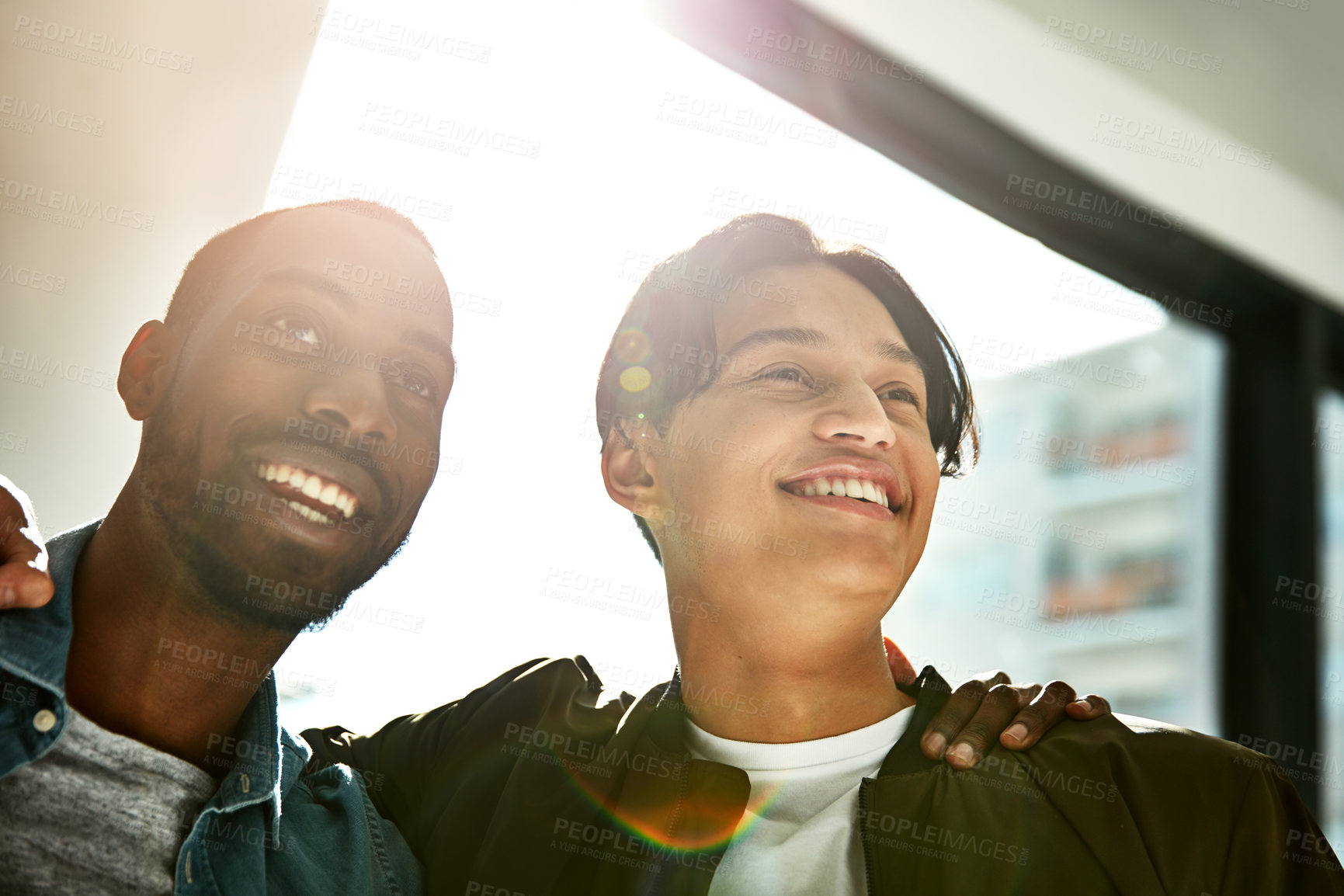 Buy stock photo Shot of two happy colleagues posing with their arms around each other in the office