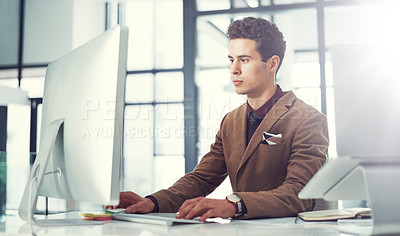 Buy stock photo Shot of a young businessman using a computer at his work desk