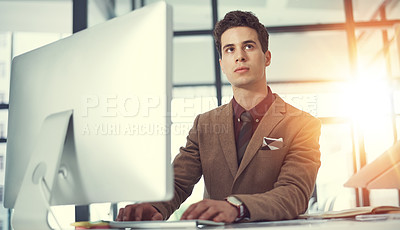 Buy stock photo Shot of a thoughtful young businessman working at his desk in a modern office