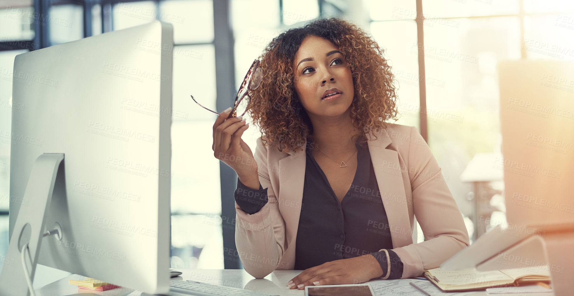 Buy stock photo Shot of a thoughtful young businesswoman working at her desk in a modern office