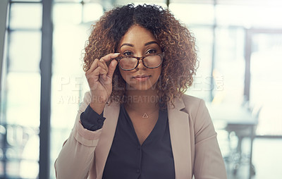 Buy stock photo Portrait of a young businesswoman peering over the rim of her glasses