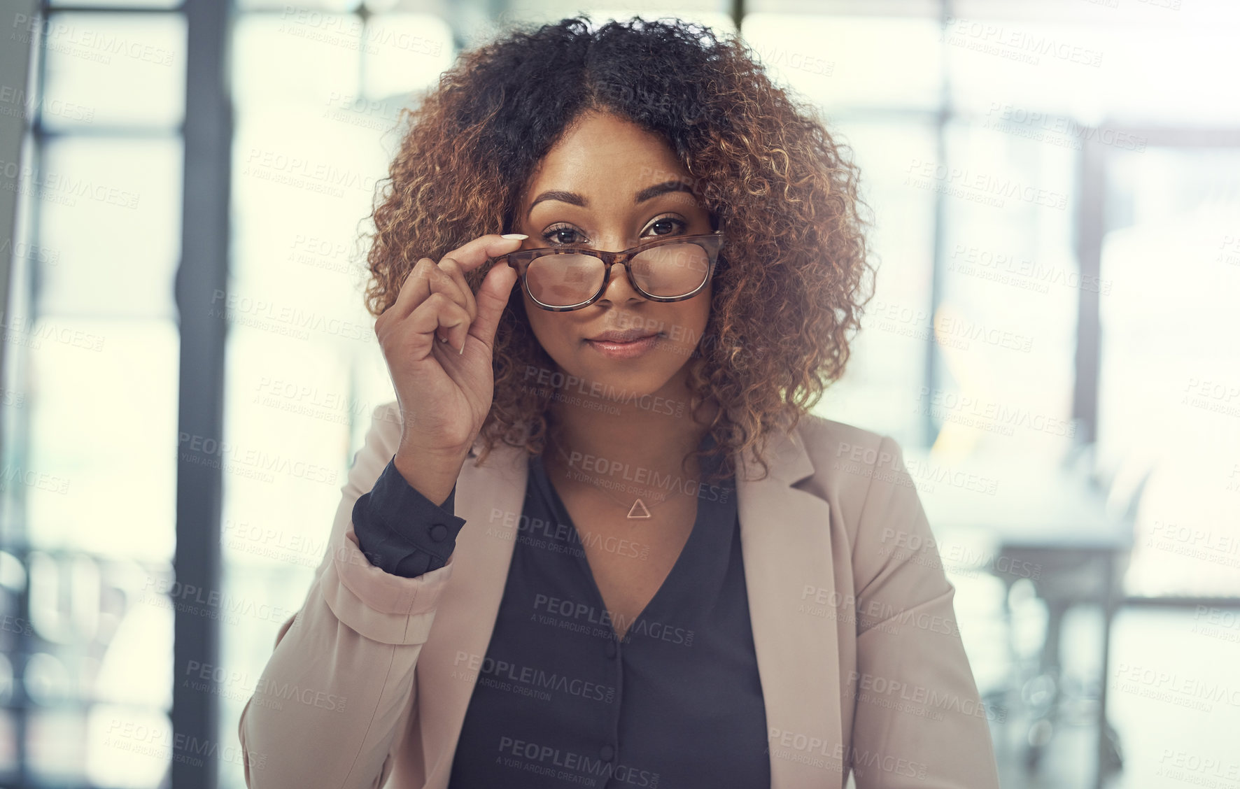 Buy stock photo Portrait of a young businesswoman peering over the rim of her glasses