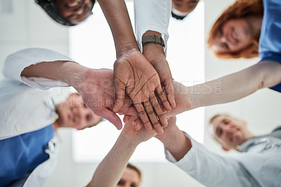Buy stock photo Low angle shot of a group of medical practitioners joining their hands together in unity