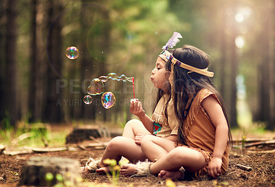 Buy stock photo Shot of two young kids blowing bubbles while playing dressup in the woods