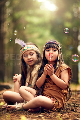 Buy stock photo Shot of two young kids blowing bubbles while playing dressup in the woods