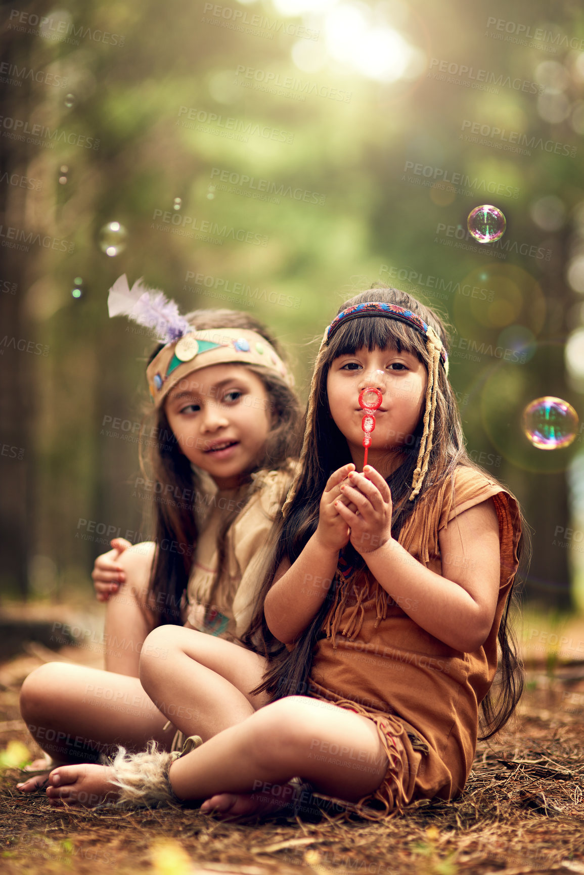 Buy stock photo Shot of two young kids blowing bubbles while playing dressup in the woods