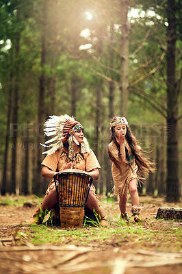 Buy stock photo Shot of a young woman banging a drum while playing dressup with her daughter in the woods