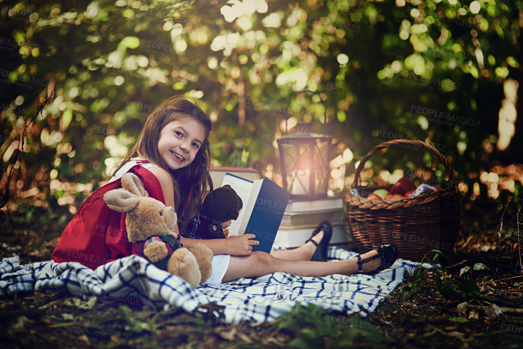 Buy stock photo Portrait of a little girl reading a book with her toys in the woods