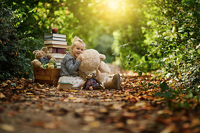 Buy stock photo Shot of a little girl reading to her toys while out in the woods