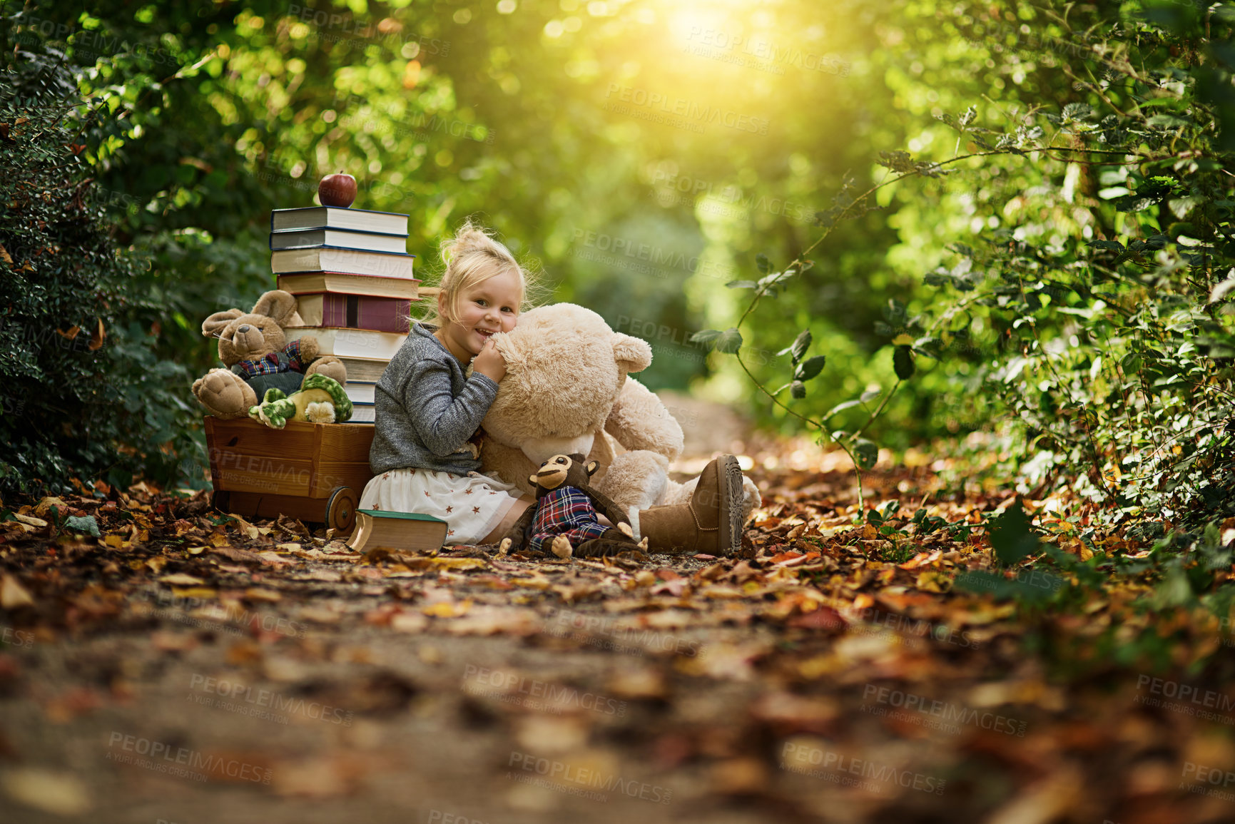 Buy stock photo Shot of a little girl reading to her toys while out in the woods