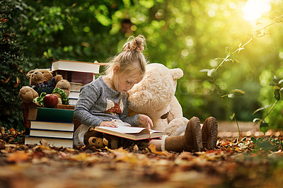 Buy stock photo Shot of a little girl reading to her toys while out in the woods