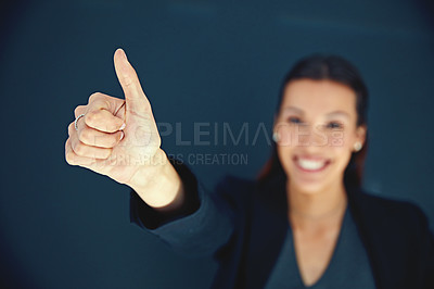 Buy stock photo Portrait of a young businesswoman showing a thumbs up against a dark background