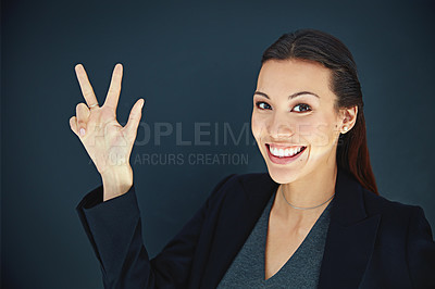 Buy stock photo Portrait of a young businesswoman showing a number with her fingers against a dark background
