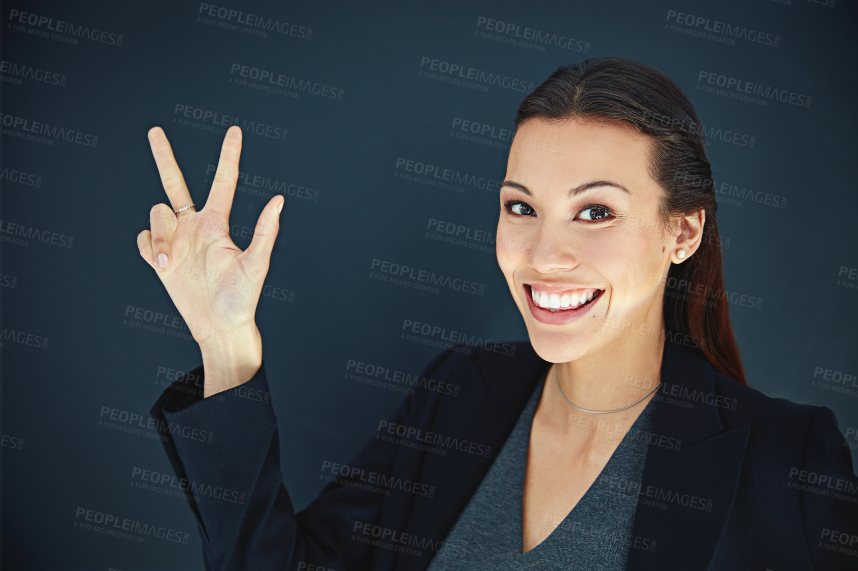 Buy stock photo Portrait of a young businesswoman showing a number with her fingers against a dark background