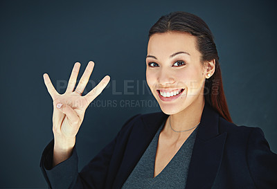 Buy stock photo Portrait of a young businesswoman showing a number with her fingers against a dark background