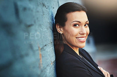 Buy stock photo Portrait of a confident young businesswoman posing against a brick wall with her arms crossed