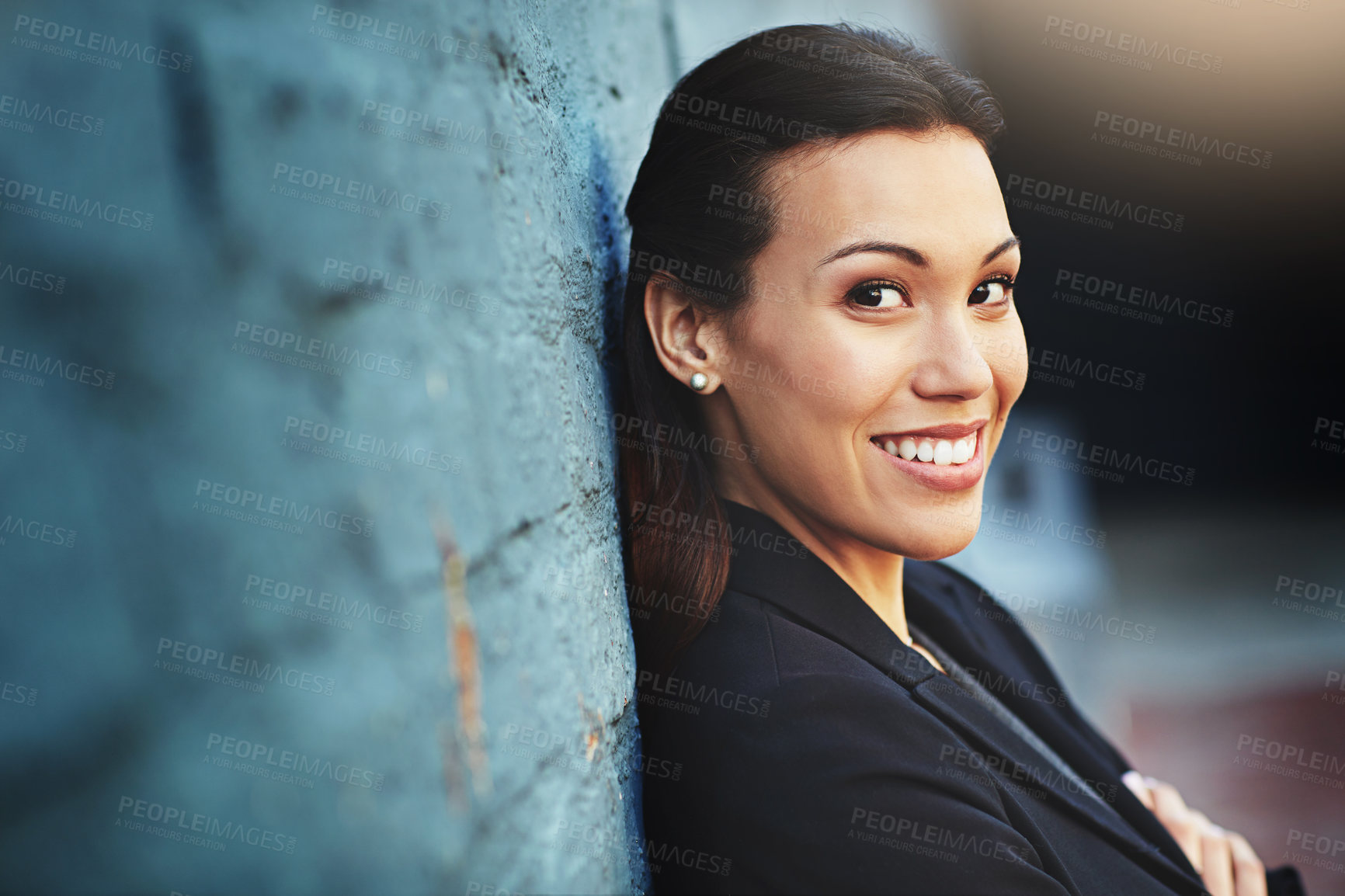 Buy stock photo Portrait of a confident young businesswoman posing against a brick wall with her arms crossed