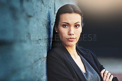Buy stock photo Portrait of a confident young businesswoman posing against a brick wall with her arms crossed