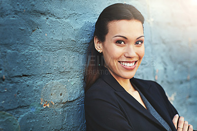 Buy stock photo Portrait of a confident young businesswoman posing against a brick wall with her arms crossed