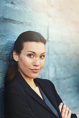 Buy stock photo Portrait of a confident young businesswoman posing against a brick wall with her arms crossed