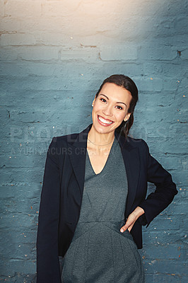 Buy stock photo Portrait of a confident young businesswoman posing against a brick wall