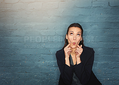 Buy stock photo Shot of a silly businesswoman pulling a funny face while posing against a brick wall