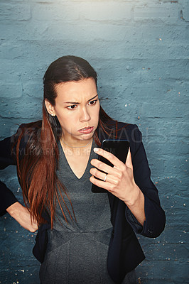 Buy stock photo Shot of an angry businesswoman looking at her phone in exasperation
