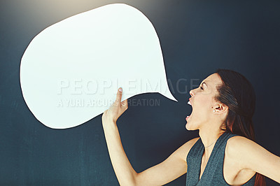 Buy stock photo Shot of a young woman shouting with a speech bubble against a gray background