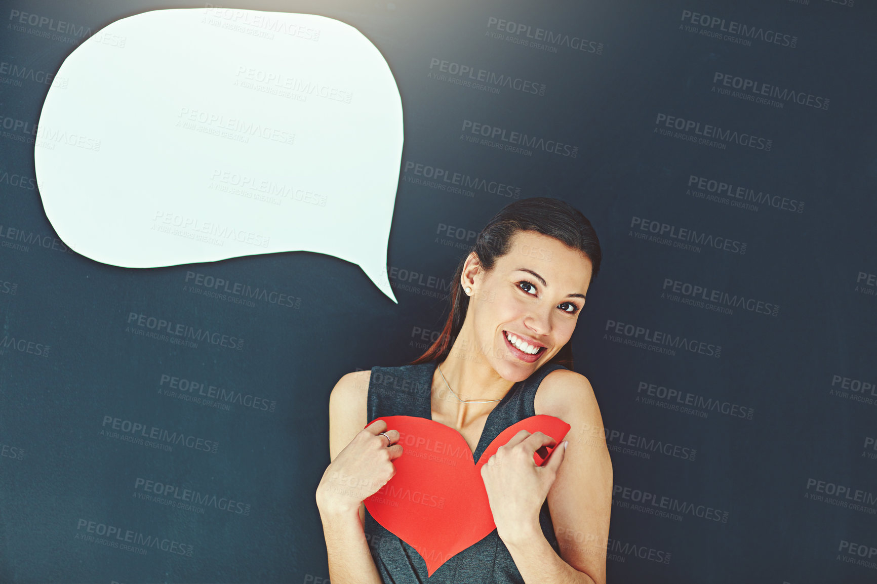 Buy stock photo Portrait of a young woman posing with a heart against a gray background